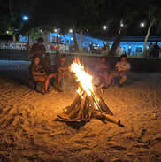 Guests gathered around a beach bonfire at night